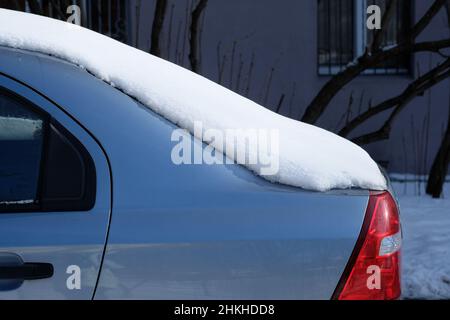 Die Rückseite des Autos Nahaufnahme im Winter. Schnee auf dem Dach und der Rückseite des Autos. Auto im Hof mit Schnee bedeckt. Stockfoto