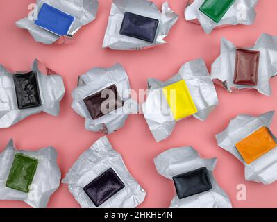 Küvetten mit Farben in Folienverpackung, Draufsicht. Neue Aquarellfarben in verschiedenen Farben. Farben in Kunststoffbehältern in Nahaufnahme. Stockfoto