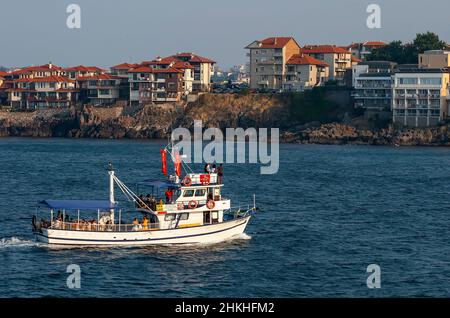 SOZOPOL, BULGARIEN - 27. JULI 2011: Eine Promenade Yacht Schlittschuhe Touristen auf dem Schwarzen Meer vor dem Hintergrund der modernen Privathäuser und modischen ho Stockfoto