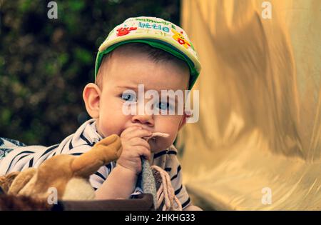 Überrascht niedliches Baby in einem Hut, der auf einem Bauch liegt und den Betrachter ansieht Stockfoto