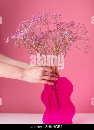 Hände setzen getrocknete Blumen Büschel in Vase. Valentinstag-Konzept. Frau Dekoration Haus mit floralen Komposition. Hochwertige Fotos Stockfoto