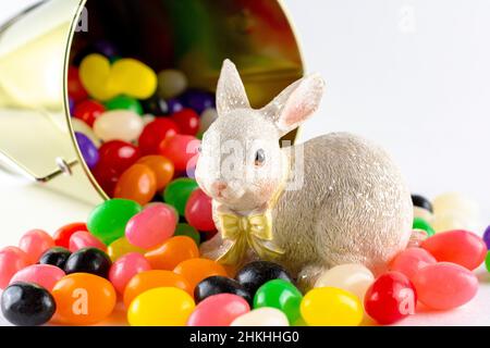 Eine Osterhasen-Figur, umgeben von verschiedenen Gelee-Bohnen aus verschütteten Eimer. Nahaufnahme. Stockfoto