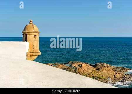 Mauern und Wachhaus der alten Festung mit dem Meer und Steinen im Hintergrund in der Stadt Salvador in Bahia Stockfoto