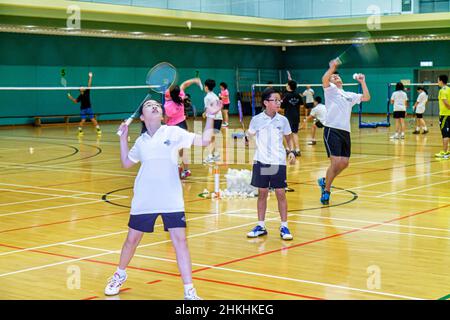 Hong Kong Chinese Island, Hong Kong Park Sports Center, Center, Badminton Courts Indoor Gymnasium, Asian Boys girl students practicing serving Stockfoto