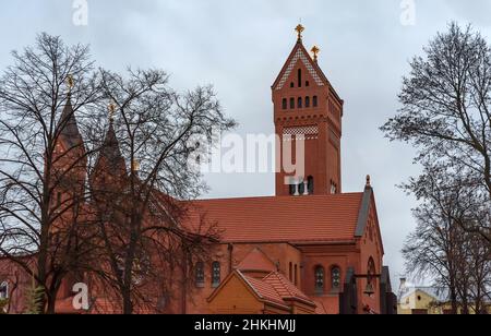 Rote Backstein-katholische Kirche St. Simon und St. Helena mit großen bewölkten Himmel in Minsk, Weißrussland Stockfoto