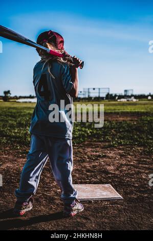 Junges Mädchen mit Pferdeschwanz üben schwingen einen Baseballschläger. Stockfoto