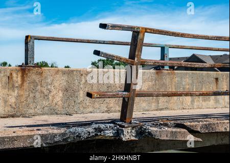 Beschädigte und verbogene Leitplanke entlang der Kante einer Brücke, die repariert werden muss. Stockfoto