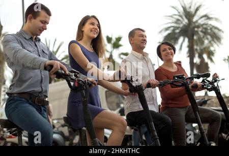 Freunde von Touristen verschiedener Generationen genießen eine Fahrt mit Elektrorollern Stockfoto