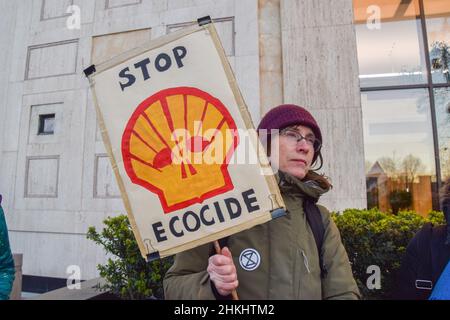 London, Großbritannien 4th. Februar 2022. Ein Protestler hält ein Schild mit dem Titel „Stop Ecocide“ vor dem Shell-Hauptquartier. Aktivisten marschierten mit einem Modellwal vom Parliament Square zum Londoner Hauptquartier von Shell, um gegen die Zerstörung der Ozeane und der Meereswelt durch Fracking, Bohrungen, seismische Untersuchungen und Verschmutzung durch Ölfirmen zu protestieren. Kredit: Vuk Valcic / Alamy Live Nachrichten Stockfoto