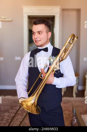 Morgen des Bräutigams. Junger Bräutigam professioneller Trompeter mit Trompete in den Händen. Stockfoto