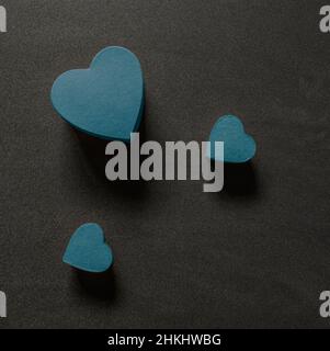 Drei blaue Herzformen auf schwarzem Hintergrund von oben Stockfoto