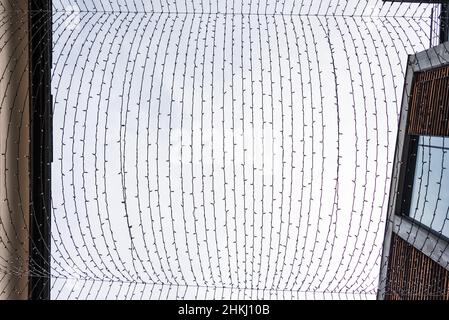 Festliche dekorative Lichter hingen von unten zwischen den Häusern. Stockfoto