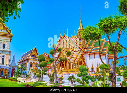 BANGKOK, THAILAND - 12. MAI 2019: Der Blick auf Phra Thinang Dusit Maha Prasat durch künstlerisch getrimmte Bäume des Rathakit-Feldes im Grand Palace, ON Stockfoto