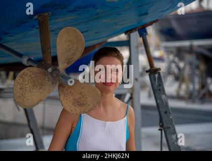 Reife Frau posiert im Trockendock neben dem Propeller einer Yacht in Spanien Teneriffa Stockfoto