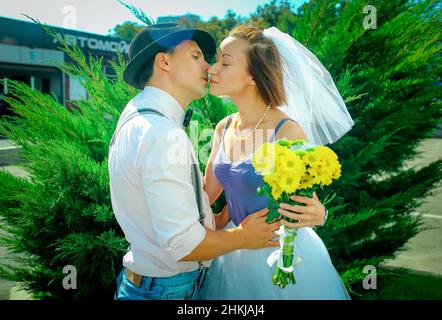 Jubiläumskuss. Ein Mann gibt einen Strauß von weiß-gelben Blumen auf einem Date im Freien. Stockfoto