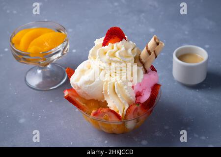 Leckeres Eis mit Früchten und Schlagsahne auf einem grauen Tisch Stockfoto