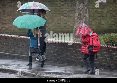 London, Großbritannien. 4th. Februar 2022. Eine Frau mit ihren Kindern geht an einer Straße entlang, während sie bei Regen Regenschirme hält. (Bild: © Steve Taylor/SOPA Images via ZUMA Press Wire) Bild: ZUMA Press, Inc./Alamy Live News Stockfoto