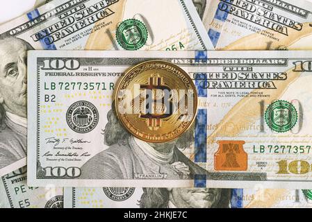 Nahaufnahme von Bitcoin auf Benjamin franklin's Gesicht auf Stapeln mit $100 Geldscheinen. Stockfoto