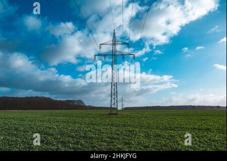 Hohe Stromlinie über einem Feld bei Sonnenschein Stockfoto