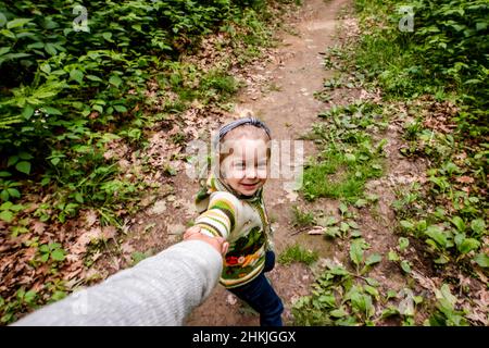 Mädchen zieht Mama im Wald auf einer Wanderung Stockfoto