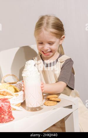 Nettes kleines Mädchen, das Kekse mit Milchshake isst Stockfoto