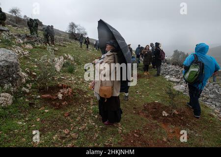 Der israelische Friedensaktivist beobachtet die Soldaten und Siedler neben den gepflanzten jungen Olivenbäumen. Hunderte von israelischen und palästinensischen Friedensaktivisten hatten im palästinensischen Dorf Burin, unterhalb des jüdischen illegalen Außenpostens von Givát Ronen, Olivenbäume gepflanzt. Zwei Wochen vor der Veranstaltung wurde eine Gruppe jüdischer Friedensaktivisten, die zur Olivenplantage eintrafen, von der Jugend von Givát Ronen gewaltsam angegriffen. Heute hatten sich die IDF-Truppen zwischen den Aktivisten und den Siedlern getrennt. Ein israelischer Aktivist wurde während der Veranstaltung verhaftet. Burin, Palästina. Februar 04th 2022. (Foto von Matan Golan/Sipa USA) Stockfoto
