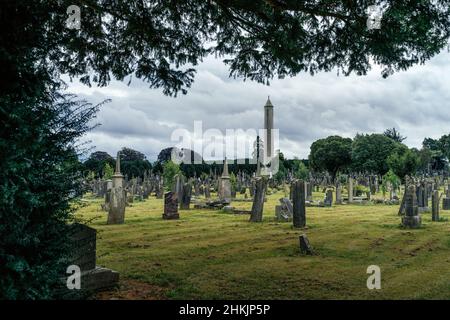 Dublin, Irland, August 2019 Antike Gräber und Grabsteine auf dem Friedhof von Glasnevin mit rundem Turm im Hintergrund Stockfoto