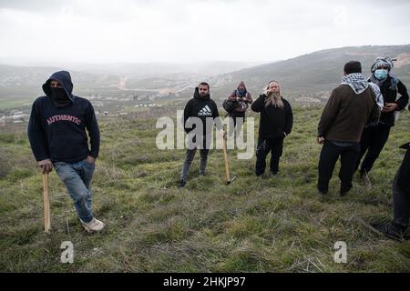Burin, Palästina. 04th. Februar 2022. Rabbi von Givát Ronen vor den Palästinensern mit Grabwerkzeugen. Hunderte von israelischen und palästinensischen Friedensaktivisten hatten im palästinensischen Dorf Burin, unterhalb des jüdischen illegalen Außenpostens von Givát Ronen, Olivenbäume gepflanzt. Zwei Wochen vor der Veranstaltung wurde eine Gruppe jüdischer Friedensaktivisten, die zur Olivenplantage eintrafen, von der Jugend von Givát Ronen gewaltsam angegriffen. Heute hatten sich die IDF-Truppen zwischen den Aktivisten und den Siedlern getrennt. Ein israelischer Aktivist wurde während der Veranstaltung verhaftet. Burin, Palästina. Februar 04th 2022. (Foto von Matan Gola Stockfoto