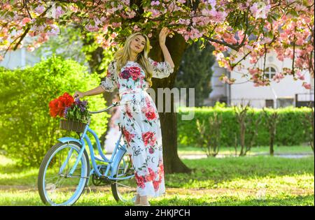 Romantische Fahrradtour. Mädchen langes Kleid Retro Cruiser Fahrrad Sakura Baum. Frühlingsferien. Tourismuskonzept. Transport und Reisen. Sakura-Saison Stockfoto