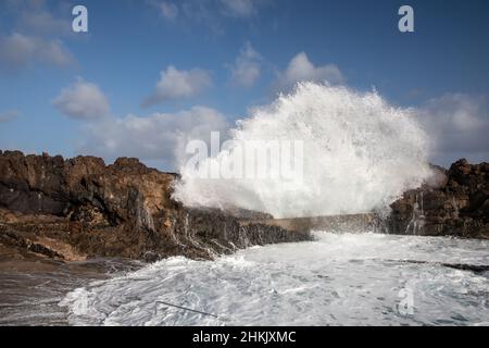 Wellen brechen an felsigen Küsten vor dem natürlichen Pool, Kanarische Inseln, Lanzarote, Charco del Palo Stockfoto