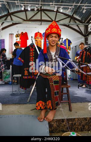 (220205) -- HAIKOU, 5. Februar 2022 (Xinhua) -- das Aktenfoto zeigt Huang Yangwei, einen 24-jährigen Mann der ethnischen Minderheit von Li, der am 27. November 2021 in der südchinesischen Provinz Hainan den ethnischen Brokat von Li webt. Das immaterielle kulturelle Erbe des Li Brokates kann bis vor über 3.000 Jahren zurückreichen. Im Einklang mit der Li-Tradition werden die Brokatwebtechniken nur „an Frauen weitergegeben, nicht an Männer“, wie im alten China Männer auf der Farm arbeiten sollten, während Frauen geweben sollten. In den letzten Jahren haben die Bildungsbehörden in Hainan den örtlichen Schulen den traditionellen Brokat eingeführt Stockfoto