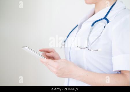 Nicht erkennbare Ärztin benutzt Handy. Der Arzt kommuniziert mit den Patienten über ein Smartphone. Abgeschnitten. Stockfoto