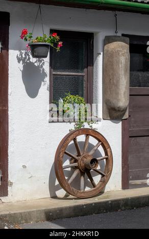 Antikes Vintage-Kutschenrad aus Holz, das an der Wand hängt. Rustikale Dekoration. Stockfoto