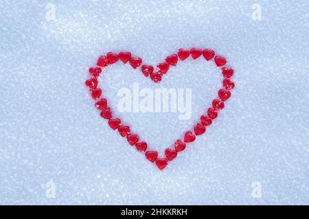 Rotes Herz mit vielen kleinen Herzen auf der Mitte des Schnees Hintergrund gemacht. Konzept für den Valentinstag oder einen romantischen Urlaub. Stockfoto