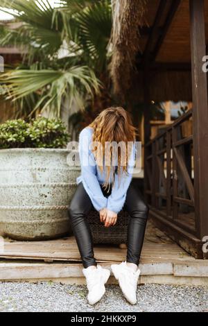 Frau sitzt im Garten, Gesicht nach unten, Depression Konzept, tief in Schwierigkeiten. Stockfoto