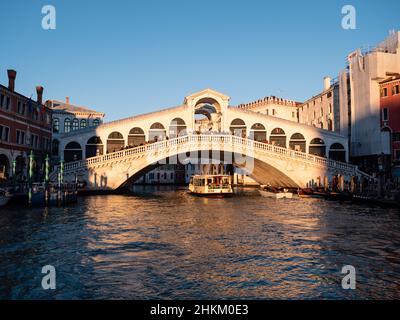 Venedig, Italien - 6 2022. Januar: Vaporetto unter der Rialtobrücke am Abend. Stockfoto