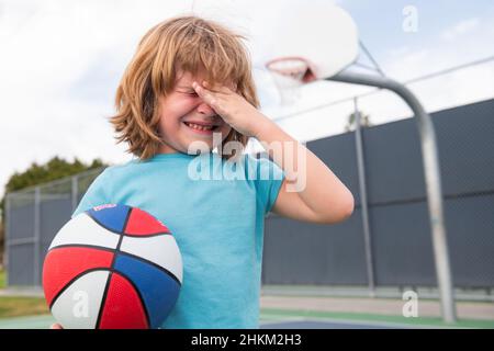 Kleiner Junge allein, einsam mit Ball. Einsamkeit Kinder. Junge weint vor Groll und Trauer. Trauriges Kind Junge Porträt. Stockfoto