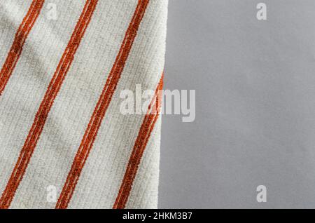 Badetuch auf grauem Hintergrund. Weißes Handtuch mit abgewinkelten roten Linien. Selektiver Fokus. Stockfoto
