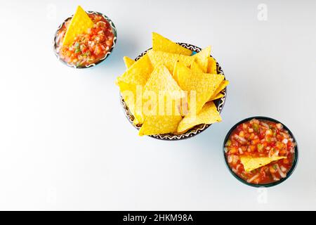 Zwei Schüsseln mit Salsa-Sauce und Nacho-Chips auf weißem Hintergrund. Tortilla-Chips und Salsa tauchen in eine Schüssel. Konzept der mexikanischen Küche. Draufsicht. Speicherplatz kopieren Stockfoto