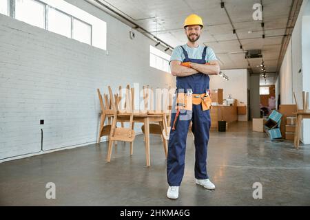 Fröhlicher Mann in der Arbeit steht in der Werkstatt Stockfoto