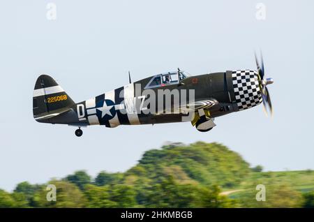 Republic P-47 Thunderbolt Kampfflugzeug aus dem Zweiten Weltkrieg in olivfarbenem Eindringling mit Invasionsstreifen und Schachbrettnasenverkleidung, die bei einer Flugshow abheben Stockfoto