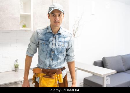 Arbeiter Mann hält Bauwerkzeug. Männliche Hand und Hut für die Renovierung des Hauszimmers. Renovierungskonzept für das Haus Stockfoto