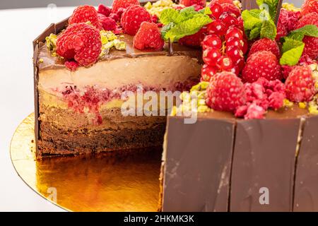 Leckere geschichtete Kuchen mit geschmolzener Schokolade Belag und dekoriert mit Himbeeren, close up Stockfoto