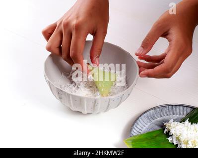 Lupis, indonesischer traditioneller Snack aus klebriges Reis, verpackt mit Bananenblatt, Shape Triangle serviert mit flüssigem Palmzucker und geriebener Kokosnuss Stockfoto