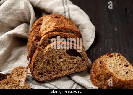 Traditionelles Dinkel-Sauerteig-Brot in Scheiben geschnitten auf einem rustikalen Holzhintergrund, rustikale Textur von Brot Stockfoto