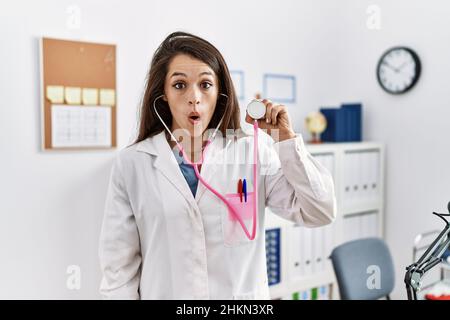 Junge Ärztin im Doktor Mantel mit Stethoskop erschrocken und erstaunt mit offenem Mund für Überraschung, Unglauben Gesicht Stockfoto