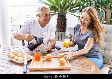 Das hispanische Paar mittleren Alters lächelte und freute sich beim Frühstück auf der Terrasse. Stockfoto
