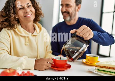 Das hispanische Paar mittleren Alters lächelte fröhlich auf dem Tisch beim Frühstück zu Hause. Stockfoto