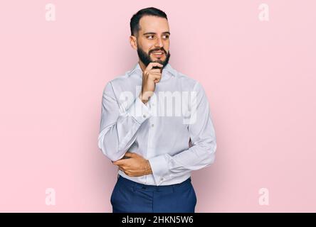 Junger Mann mit Bart trägt Business-Shirt mit Hand auf Kinn denken über Frage, nachdenklichen Ausdruck. Lächelnd mit nachdenklichen Gesicht. Zweifel Konzept Stockfoto
