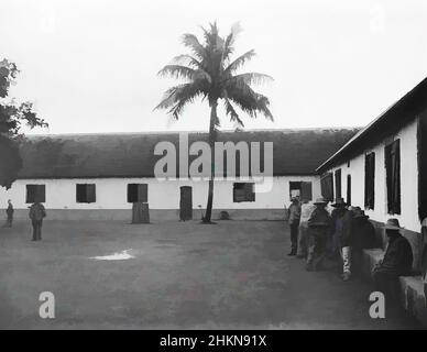 Kunst inspiriert von Convict Prison, Isles of Pines, Noumea, Burton Brothers Studio, Fotostudio, 1899, Dunedin, Schwarz-Weiß-Fotografie, einstöckiges Kolonialgebäude mit Ziegeldach, das von vorne rechts nach hinten und dann über den Hintergrund verläuft. Classic Works, ein offener Hof mit einem einfreien Kokosnussbaum, der von Artotop mit einem Hauch von Moderne modernisiert wurde. Formen, Farbe und Wert, auffällige visuelle Wirkung auf Kunst. Emotionen durch Freiheit von Kunstwerken auf zeitgemäße Weise. Eine zeitlose Botschaft, die eine wild kreative neue Richtung verfolgt. Künstler, die sich dem digitalen Medium zuwenden und die Artotop NFT erschaffen Stockfoto